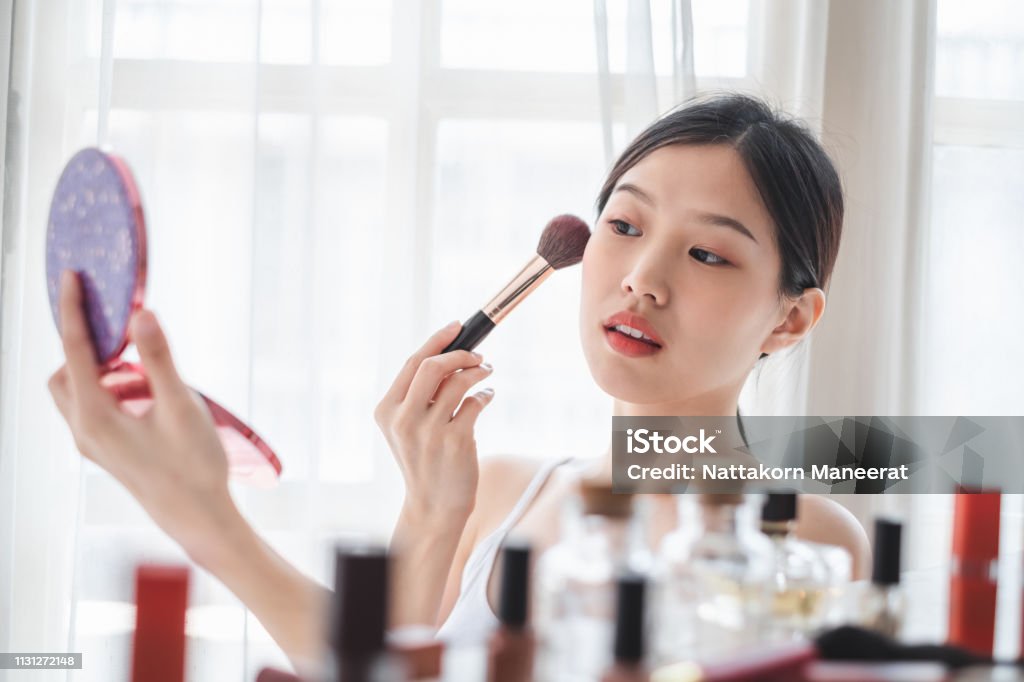 Young beautiful Asian woman applying cosmetics make up on her face, health beauty skin care and make up concept Make-Up Stock Photo