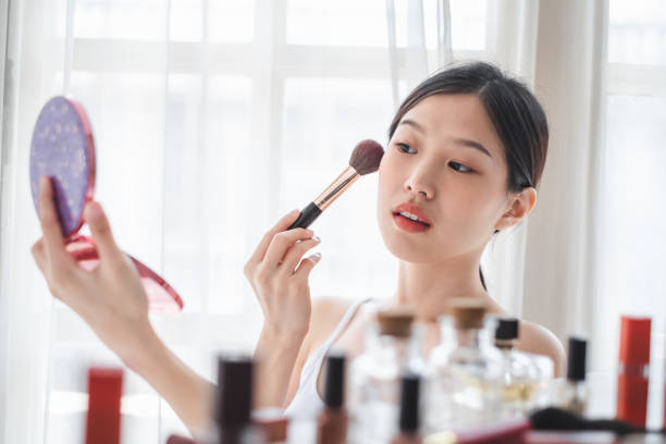 Young beautiful Asian woman applying cosmetics make up on her face, health beauty skin care and make up concept stock photo