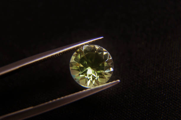 istock green amethyst  round shaped in tweezer black background 1131272253