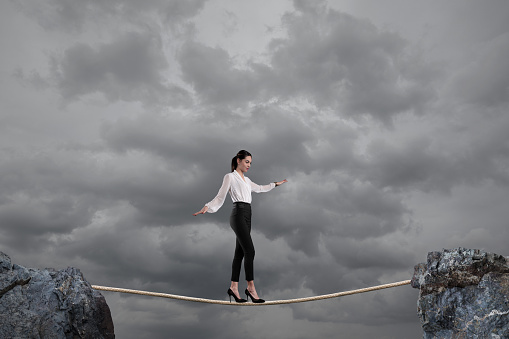Businesswoman walking on a rope.
