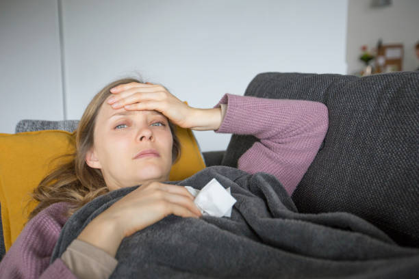 istock Sick woman holding one hand on head, having napkin in another 1131278573