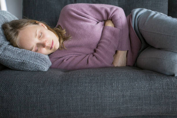 istock Sick woman lying on grey sofa at home, having legs bent 1131278575