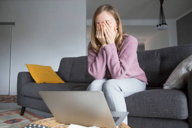 istock Woman at home closing eyes with hands, thinking. Laptop on table 1131278633