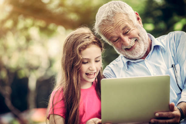 szczęśliwa rodzina za pomocą laptopa w publicznym parku. - grandmother reading child grandson zdjęcia i obrazy z banku zdjęć