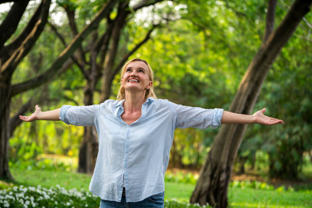 istock Happy middle aged woman standing in the park. 1131284232