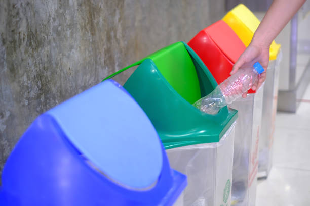 hand throwing empty plastic bottle into the trash stock photo