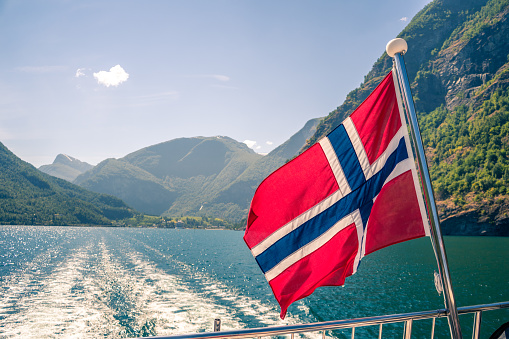 Leaving Flam port in Norway. Norwegian flag flying on the aft deck of the fjord cruise ship