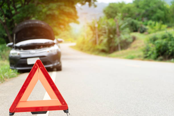 car broken down on the road with emergency help sign. car break down trouble on road, traffic warning triangle sign on asphalt road. Emergency stop concept.Red triangle of a car on nature road.Broken car in country mountain road. Damage car with reflecti