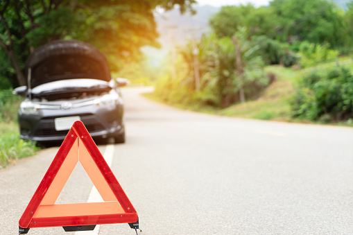 car broken down on the road with emergency help sign. car break down trouble on road, traffic warning triangle sign on asphalt road. Emergency stop concept.
Red triangle of a car on nature road.Broken car in country mountain road. Damage car with reflective triangleÂ .