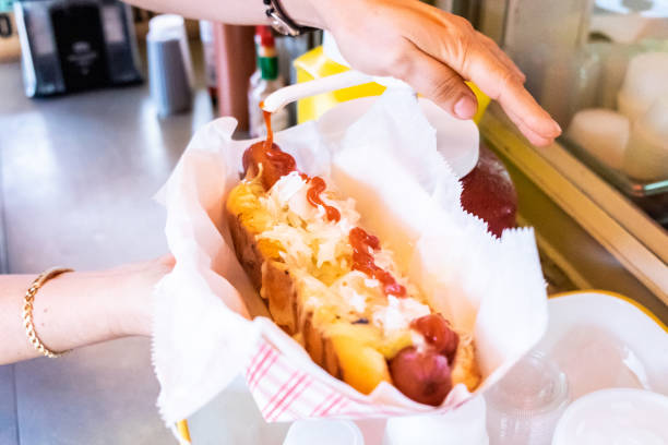 Eating junk food woman poring ketchup over a hotdog hot dog stand stock pictures, royalty-free photos & images