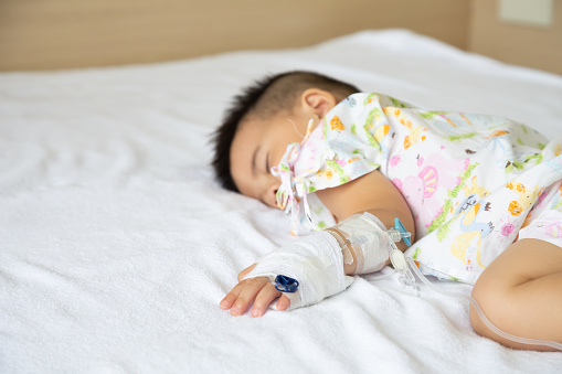 Bebé asiático durmiendo en la cama con la infusión fijada en el Departamento del niño en el hospital. Niños con enfermedades infecciosas IPD, concepto de enfermedad neumocócica invasiva. Modelo infantil un año seis meses photo