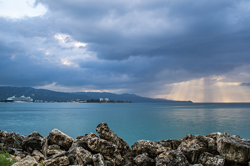 Montego Bay, Jamaica - March 20 2018: Sunburst through the clouds at sunset with Marella Discovery 2 of Marella Cruises (formerly Thomson Cruises) cruise ship docked in port.