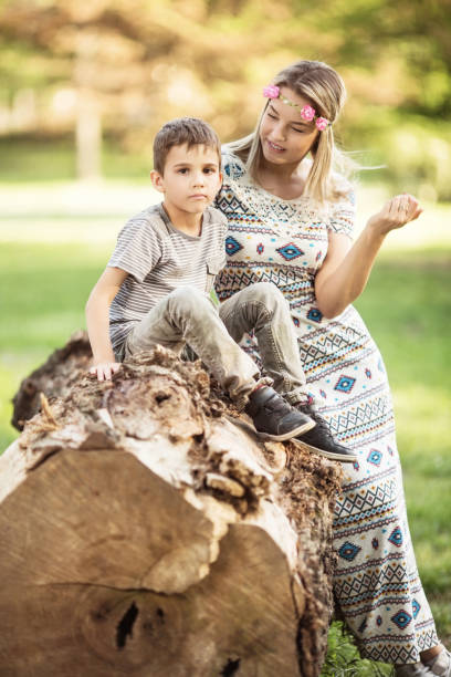 istock Mother and son sitting on a tree log outdoors 1131301618