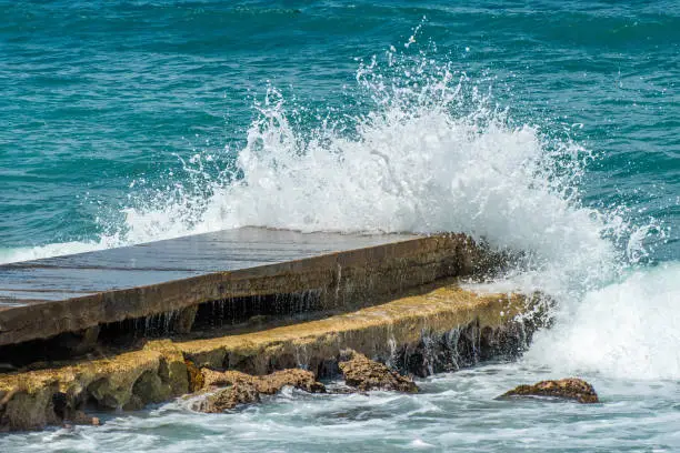 Waves crashing and splashing against a pier/ jetty/ boardwalk by the ocean