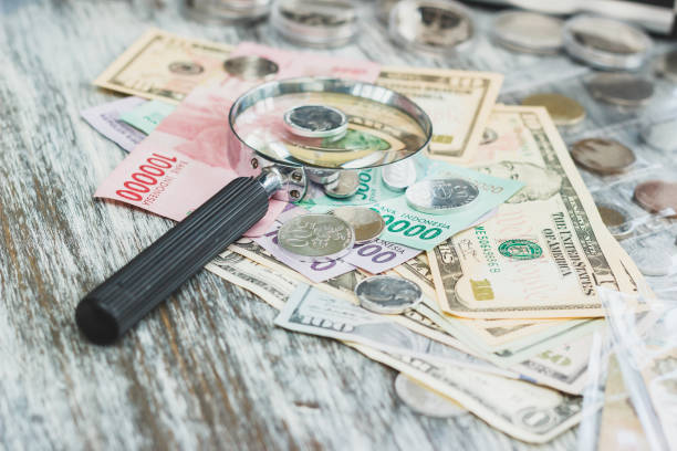 istock Different American dollars and Indonesian rupiahs and a Magnifying glass, numismatics concept 1131310968