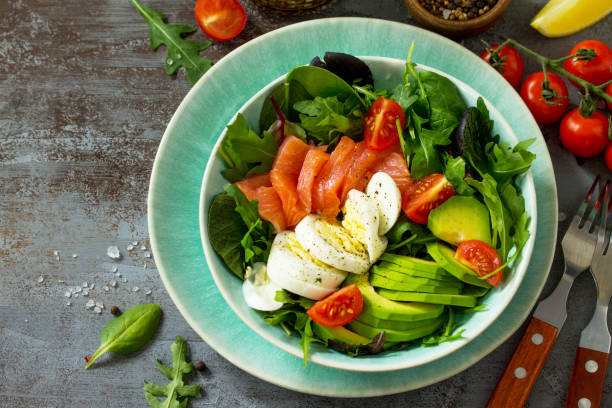 istock Diet menu concept. Summer Healthy salad with Tomatoes, Salmon, Egg, Avocado and arugula on a dark stone table. 1131316902