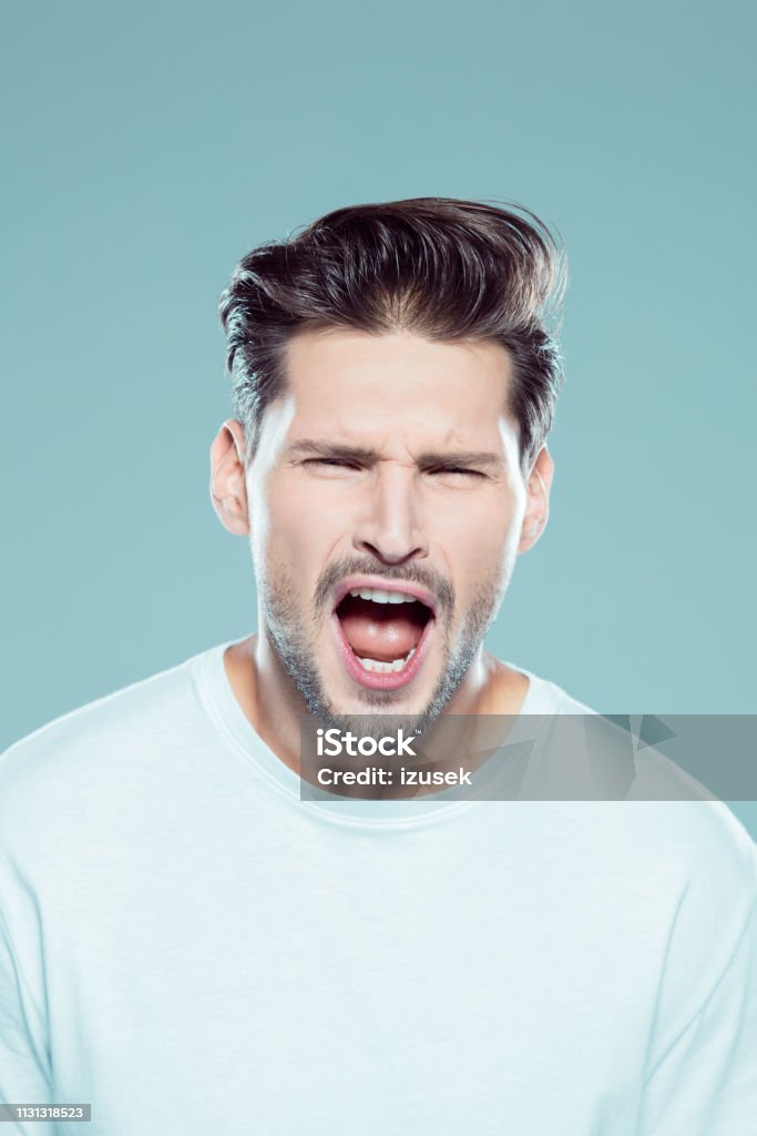 Young man shouting in excitement Close up portrait of young man shouting in excitement against gray background Human Face Stock Photo
