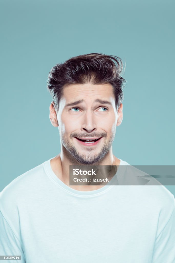Confused young man looking away Close up portrait of confused young man looking away against gray background Men Stock Photo