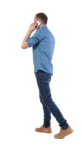 istock Back view of man walking with a mobile phone. 1131320095