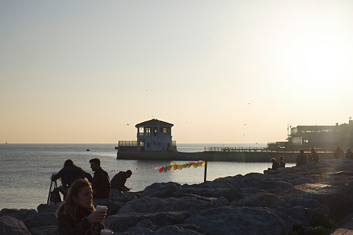Istanbul, Turkey - February 17, 2019: Residents and tourists of Kadikoy are saying goodbye to the sun, as usual, Historical Moda Port Of Moda.