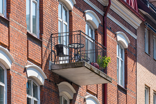 Architectural details of modern apartment building. Balcony with chairs and green flowers