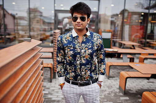 Attractive and handsome stylish indian man wear on shirt and sunglasses standing in the terrace of modern lounge cafe at his work break.