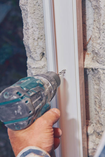 istock Worker using battery hand drill to screw into the PVC window frame. 1131330485