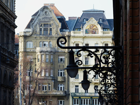 vintage decorative ornamental wrought iron wall lanterns street lighting in perspective in Budapest with classical brick exterior elevations. travel and tourism concept. street lamp close-up detail with streetscape.