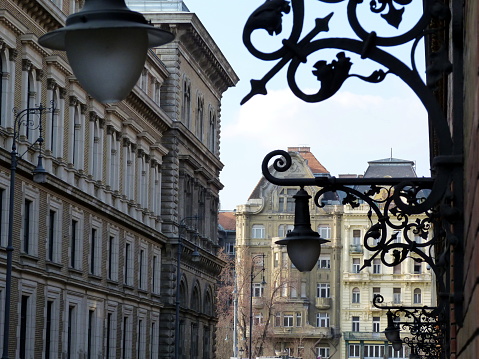 vintage decorative ornamental wrought iron wall lanterns street lighting in perspective in Budapest with classical brick exterior elevations. travel and tourism concept. street lamp close-up detail with streetscape.