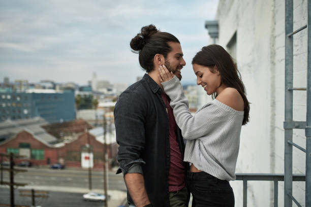 istock Romantic couple smiling while standing in balcony 1131333569