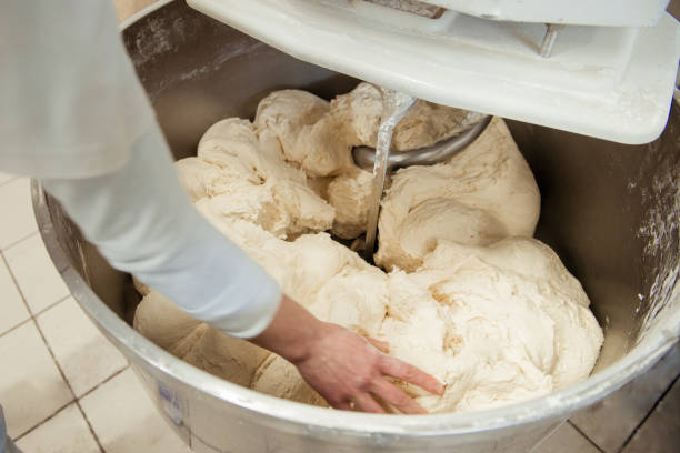panadero preparando la masa para pan en una batidora de masa - food industry manufacturing human hand fotografías e imágenes de stock