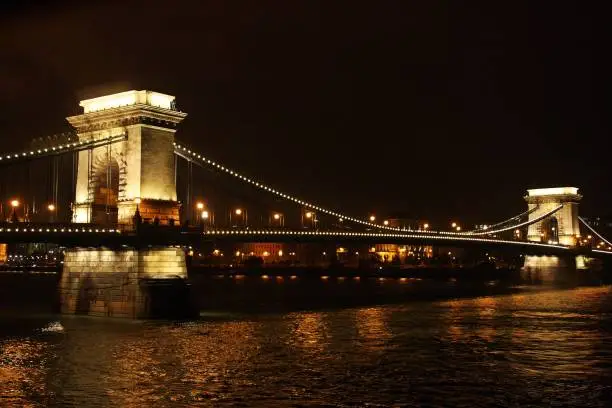 The "Széchenyi" Chain Bridge. A suspension bridge over the Danube river in Budapest, Hungary. Beautiful picture taken in the night with the bridge illuminated and the reflection of the light on the surface of the water.