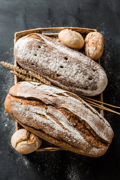 istock Bakery - rustic crusty loaves of bread and buns on black 1131340885