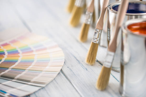 Paint cans brushes and color palette on table.