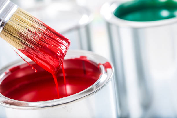 Close-up brush with red color over paint can.