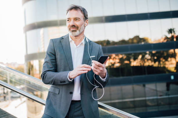 istock Man using mobile phone and in-ear headphones 1131345116