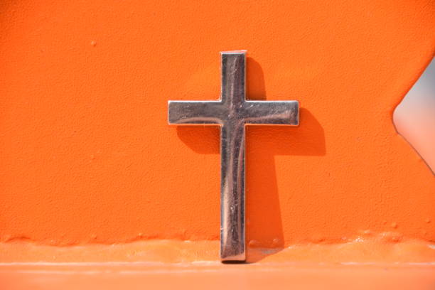 istock cross Against an orange wall 1131348548