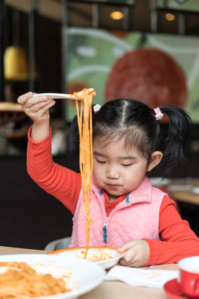 istock Cute baby girl eating spaghetti 1131350980
