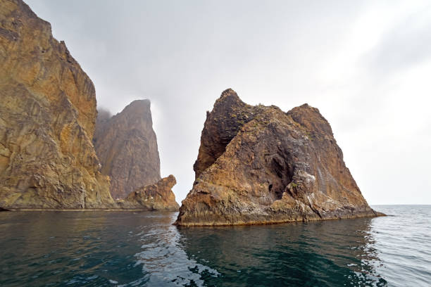 Rocky mountain coast, volcano Karadag, Crimea, cloudy gray gloomy sky, fog.