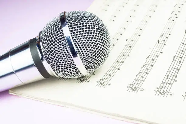 The musical microphone lies on a clean sheet music. Music concert. The singer and the song