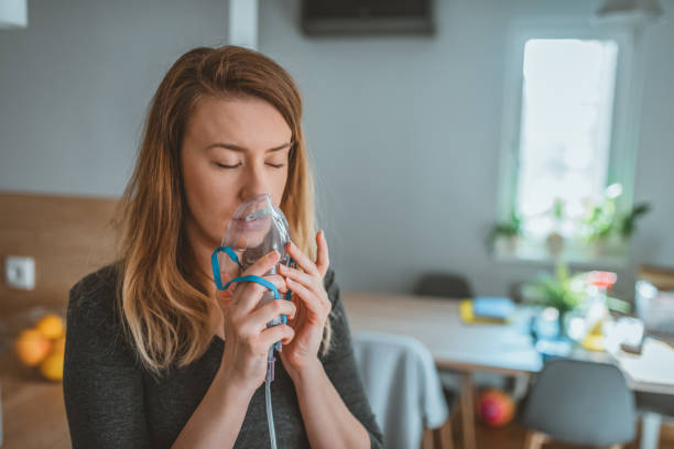 mujer joven que usa un inhalador para el asma - exhalar fotografías e imágenes de stock