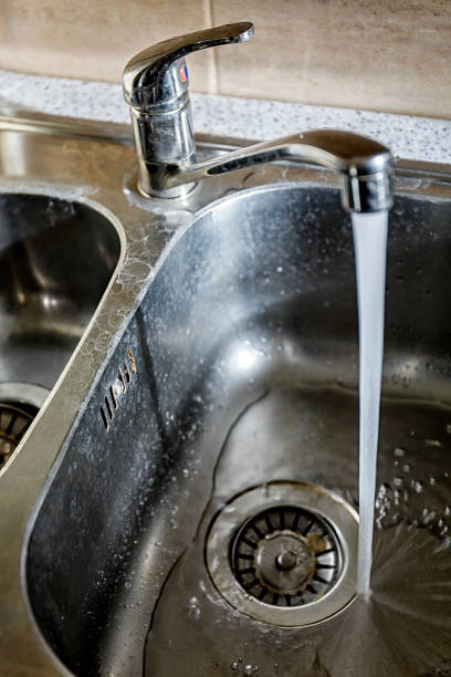 istock Close-up of a kitchen sink with lime scale and flowing water 1131353663