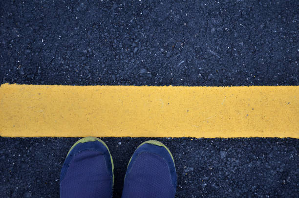 道路上の黄色の線でアスファルト地面に立って。 - single line yellow road asphalt ストックフォトと画像