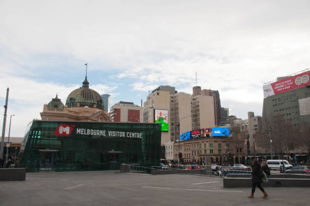 il melbourne visitor centre si trova in federation square vicino alla stazione di flinders street nel quartiere centrale degli affari di melbourne. ci sono persone sedute e che camminano in piazza. la foto viene scattata nel pomeriggio. - melb foto e immagini stock