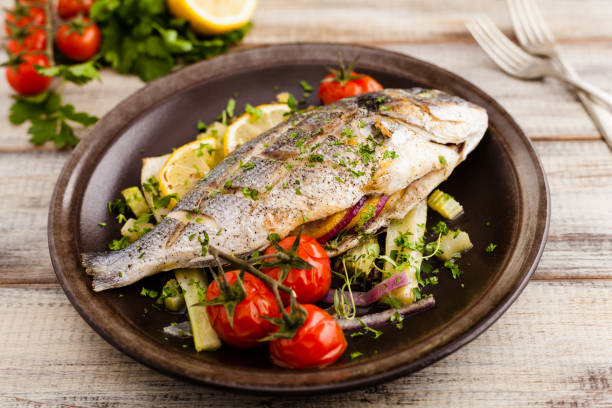 istock Baked whole fish, served with roasted vegetables and lemon. 1131357693