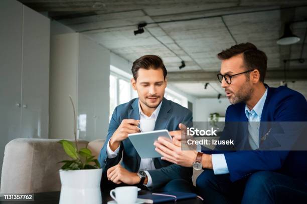 Male Professionals Discussing Over Digital Tablet Stock Photo - Download Image Now - Business Person, Working, Confidence