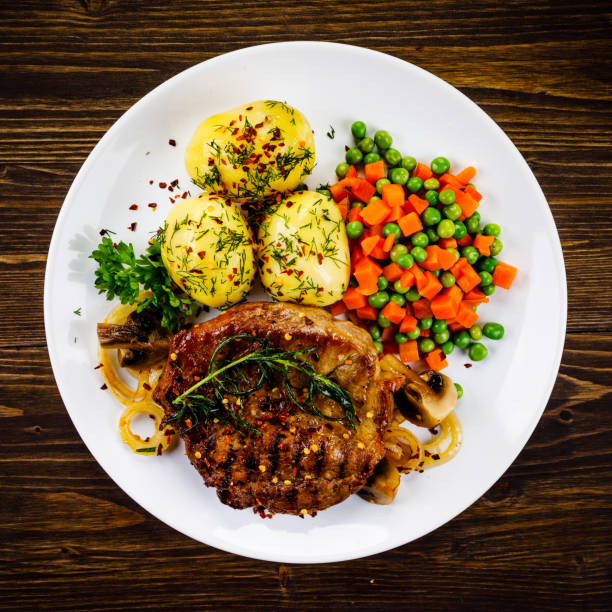 istock Barbecued steak and vegetables on wooden background 1131357925
