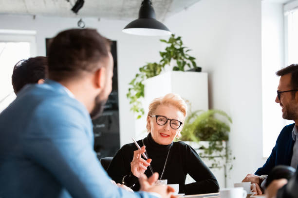 istock Smiling female manager discussing with colleagues 1131357978