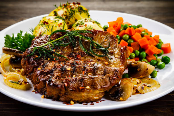 istock Barbecued steak and vegetables on wooden background 1131358003