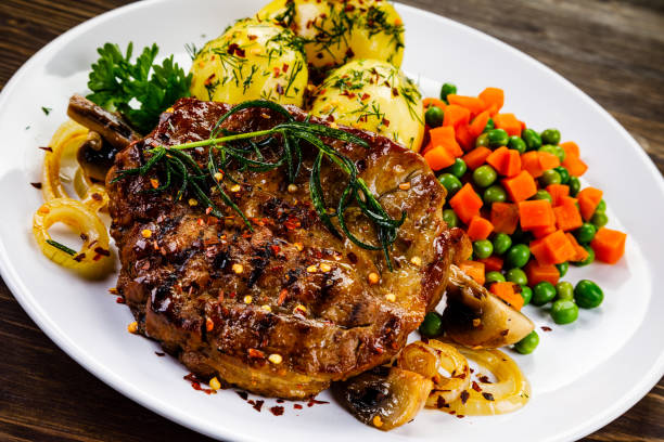 istock Barbecued steak and vegetables on wooden background 1131358193